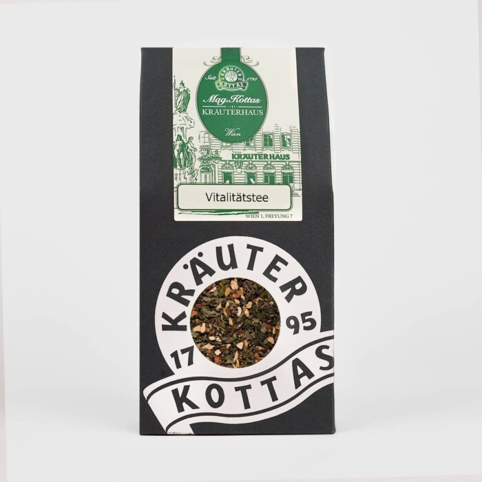 Eine Teepackung von KOTTAS Vitaltee aus dunklem Karton mit farbigen Akzenten und Blick auf die dunkle Teemischung.