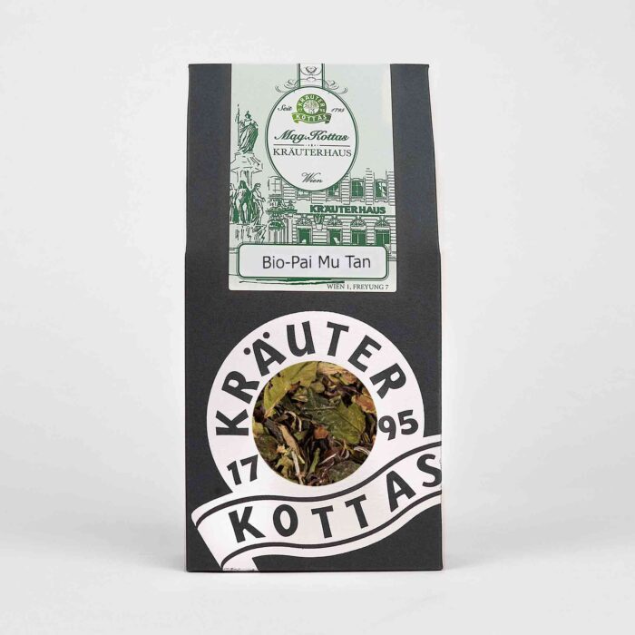 Eine Packung loser Pai Mu Tan Tee von KOTTAS. Dunkle Verpackung aus Papier mit grünem Firmenlogo und silberner Verzierung.