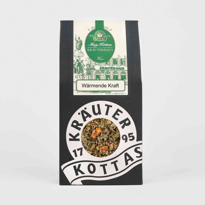 Eine Packung KOTTAS wärmende Kraft Tee in einer schwarzen Papierverpackung mit grünem Firmenlogo und einem Blickfenster auf die lose Teemischung.