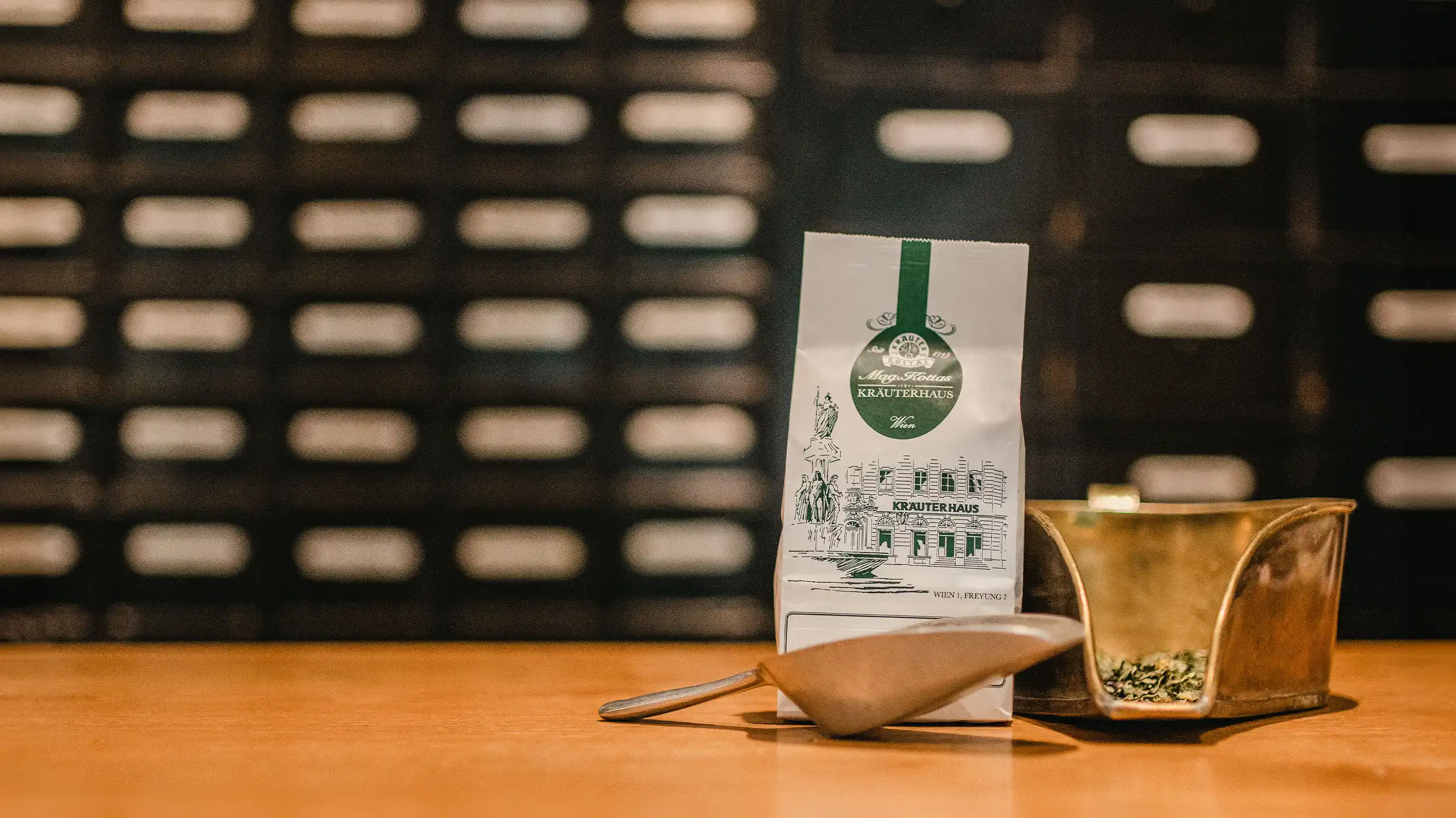 Packung Kräutertee mit Schaufel und Kräutern vor alter Schubladenwand