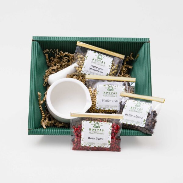 KOTTAS Kräuterhaus Pfefferbox in dunkelgrüner Kartonverpackung mit 3 verschiedenen Pfeffersorten sowie rosa Beeren in einem Cellophanbeutel und kleinem Mörser.